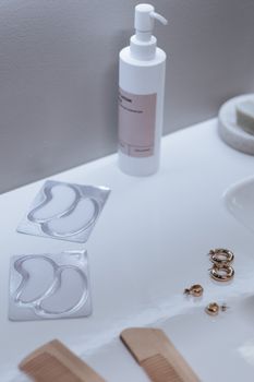 A stylish bathroom vanity featuring skincare products, jewelry, and eyepatch packaging, perfect for modern decor.