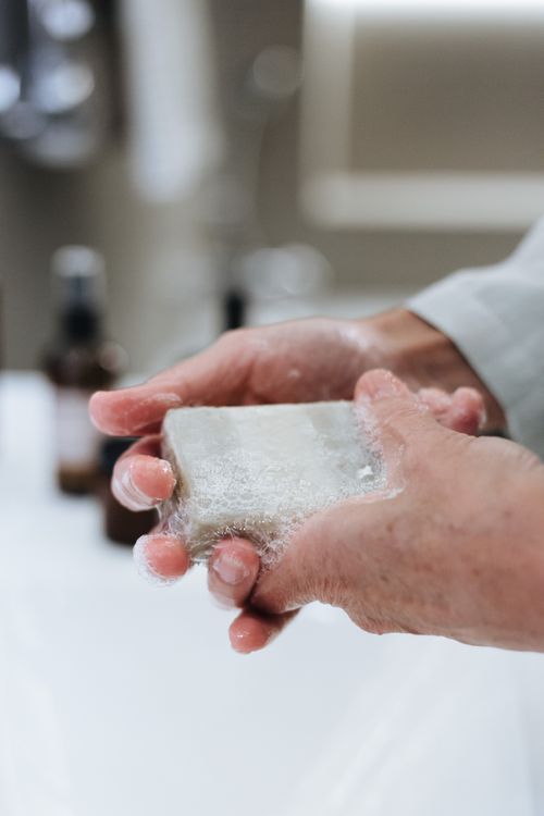 Free Hands holding a soapy bar of soap in a bathroom, emphasizing hygiene and cleanliness. Stock Photo