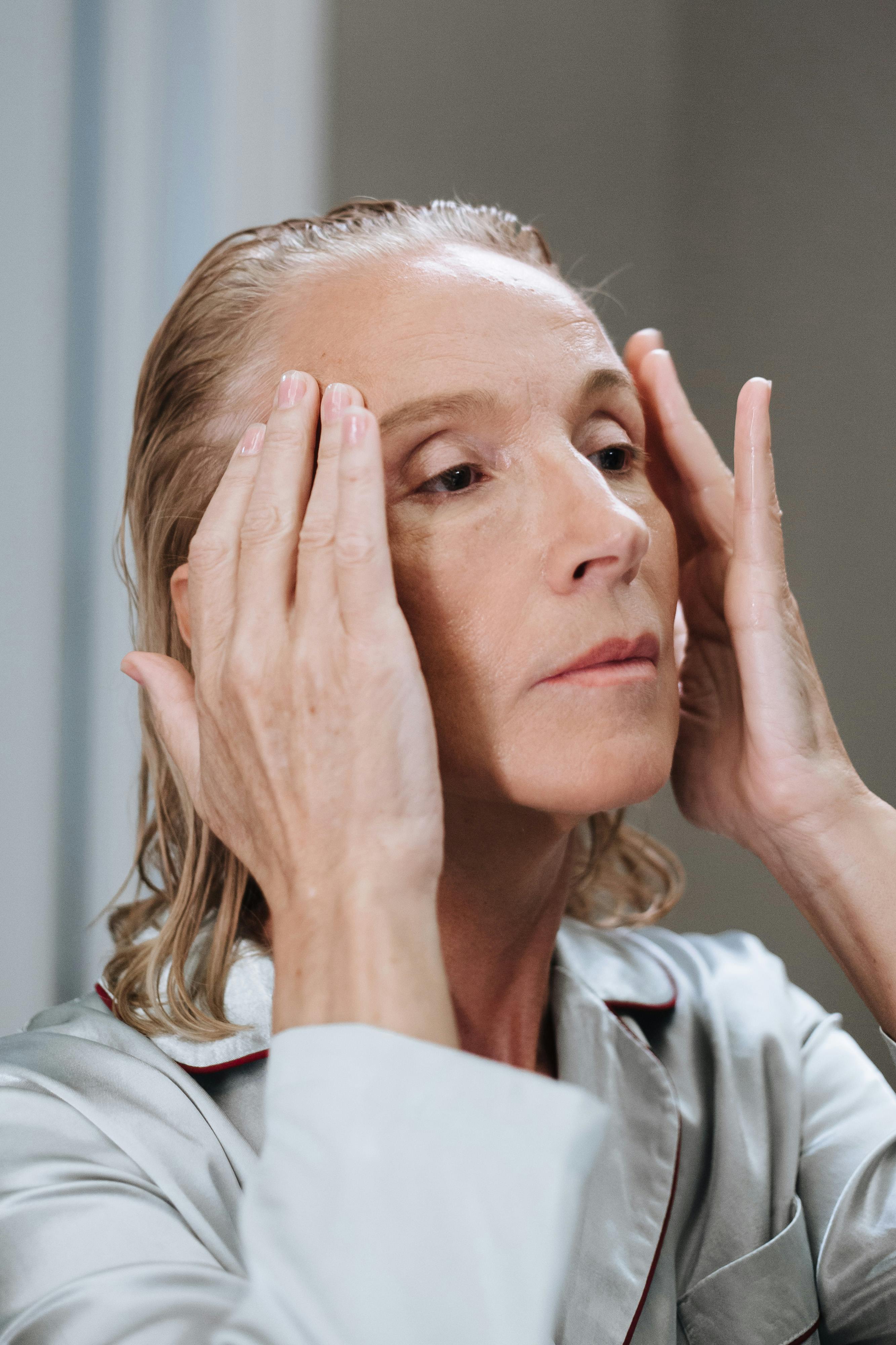 Woman practicing a face massage for skincare routine indoors.