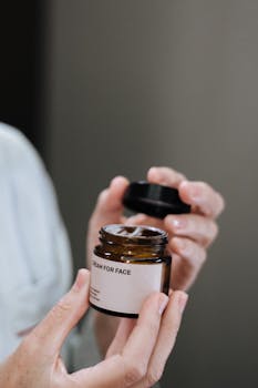 A jar of face cream held by hands, emphasizing skincare and beauty.