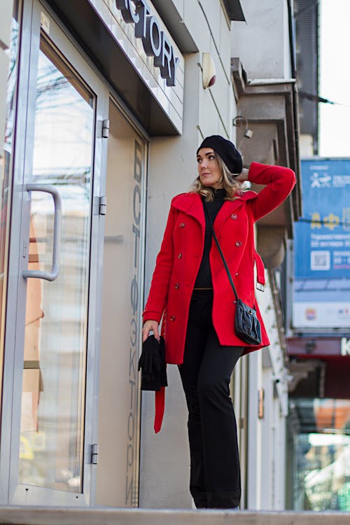Free Woman in Red Coat Standing Beside Glass Door Stock Photo