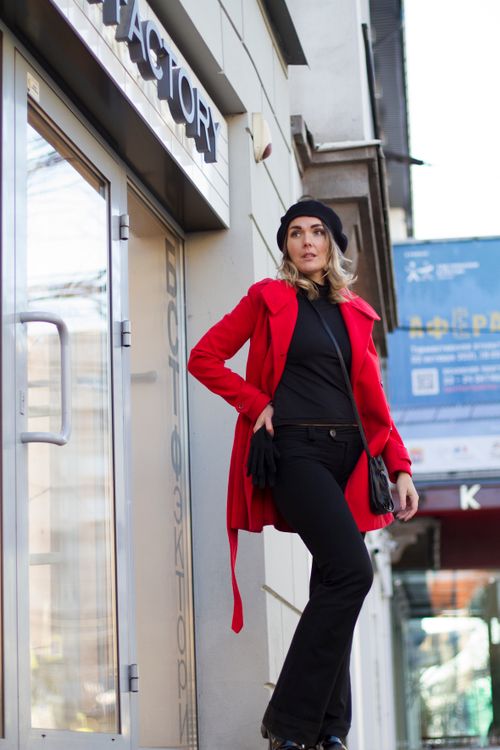 Free Fashionable woman in a red coat and beret poses confidently near a glass door outdoors. Stock Photo