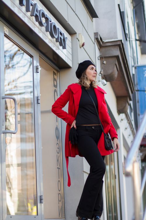 Free Fashionable woman in a red jacket poses stylishly outdoors by a city building. Stock Photo