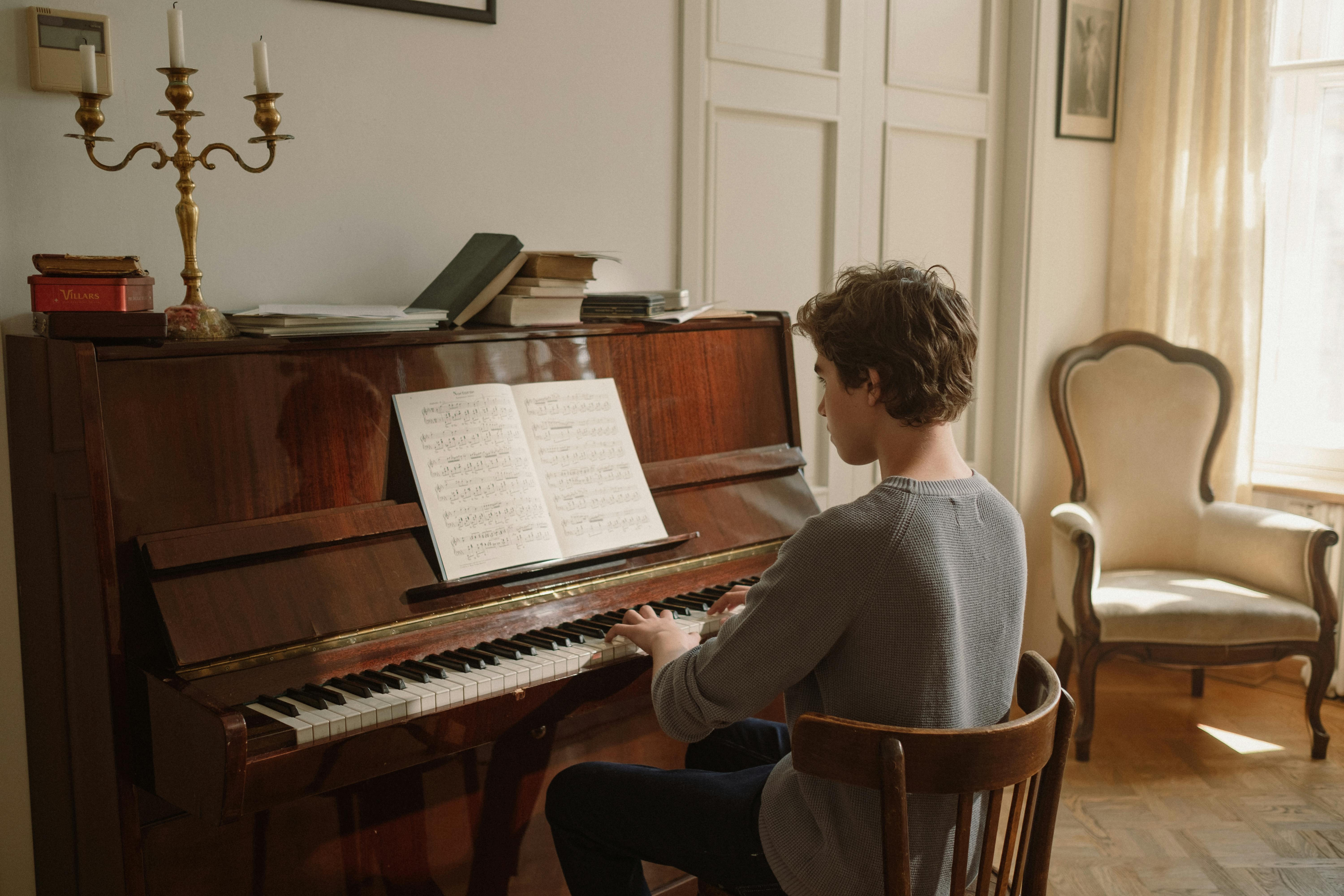 boy sitting on wooden chair playing the piano