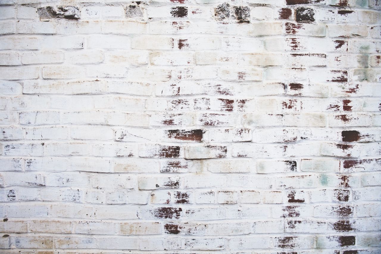 a high resolution image of a white painted brick wall with weathered t