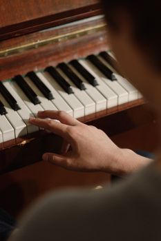 A person's hands playing piano keys indoors, creating a musical ambiance.