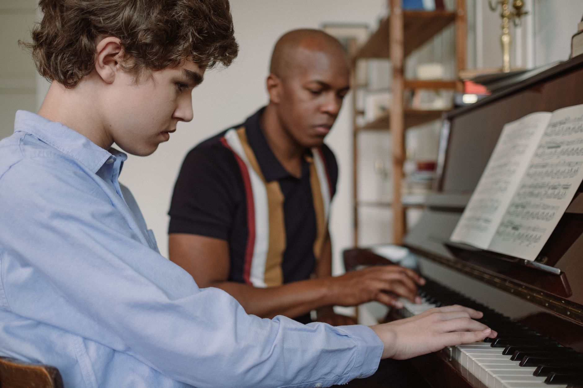 Teacher and Teenage Boy Sitting by Piano