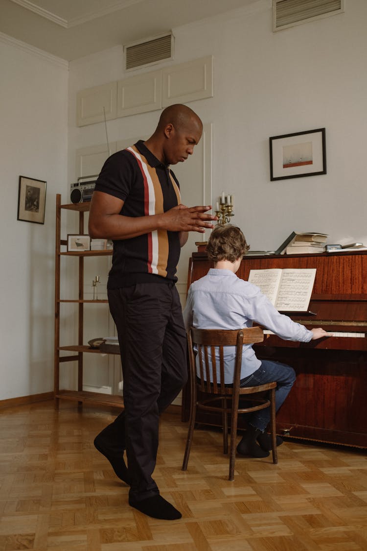 A Man Teaching A Boy To Play Piano