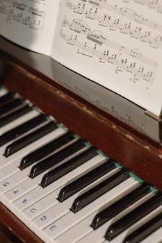Detailed view of piano keys alongside a sheet music piece, capturing a musical ambiance.