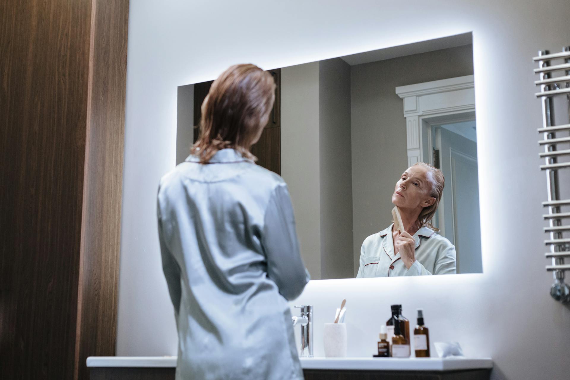 A Low Angle View of a Senior Adult Looking at Mirror During Self Care in Bathroom