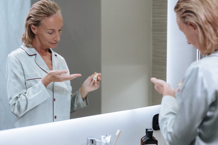 Woman Using Cosmetic Serum In Bathroom