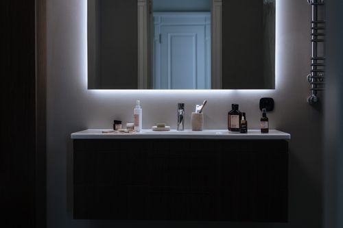 Free Sleek bathroom vanity setup with LED mirror and various cosmetic products against a modern backdrop. Stock Photo