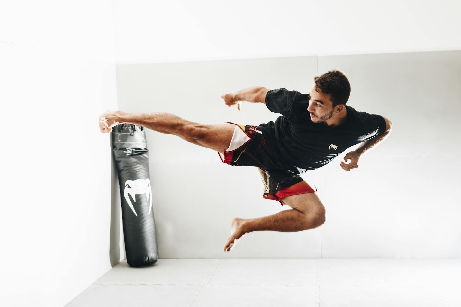 Martial artist performing a high kick with power and precision in a training room.