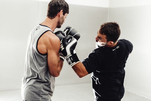 Man Wearing Black Shirt Training a Young Man in Boxing