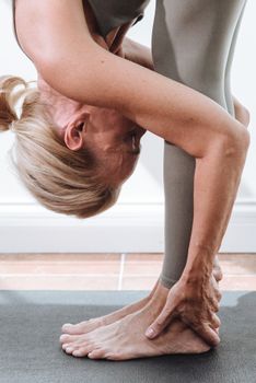 A senior woman gracefully performing yoga indoors, showcasing flexibility and healthy lifestyle.