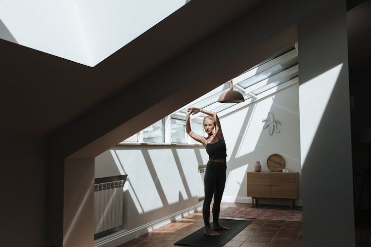 Elderly Woman Stretching In Attic Room