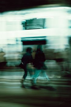 Abstract motion blur of pedestrians walking at night in Athens, Greece.