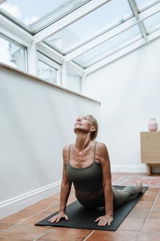 Elderly woman in yoga pose on mat in sunlit room, promoting fitness and wellness.