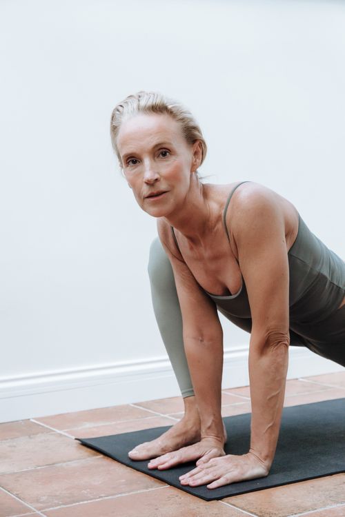 Free Senior woman in sportswear performing yoga on a mat indoors, demonstrating fitness and health. Stock Photo