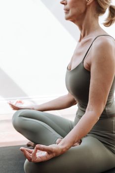 A woman in a peaceful meditation pose practicing yoga indoors, embodying mindfulness and relaxation.