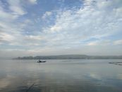 A tranquil scene of a lone boat on a lake in Trảng Bom, Vietnam, under a blue sky.