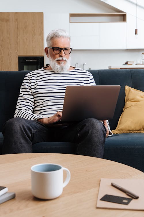 Free Man Working on Couch with Laptop Stock Photo