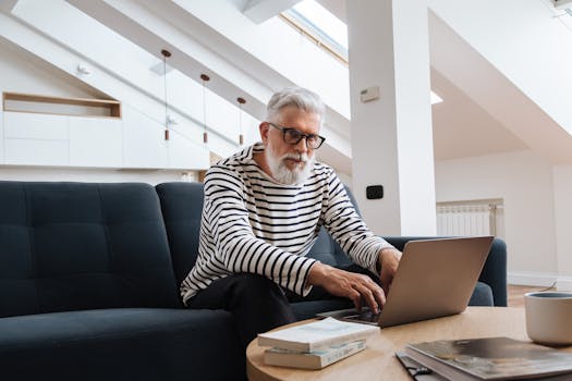 Senior man with glasses using laptop in a stylish modern living room setting.