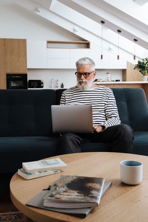 Free Man Working on Couch with Laptop with Table in front  Stock Photo
