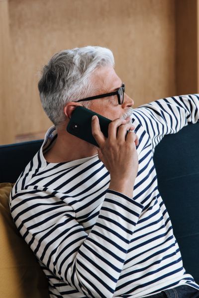Un homme âgé répond au téléphone tranquillement chez lui