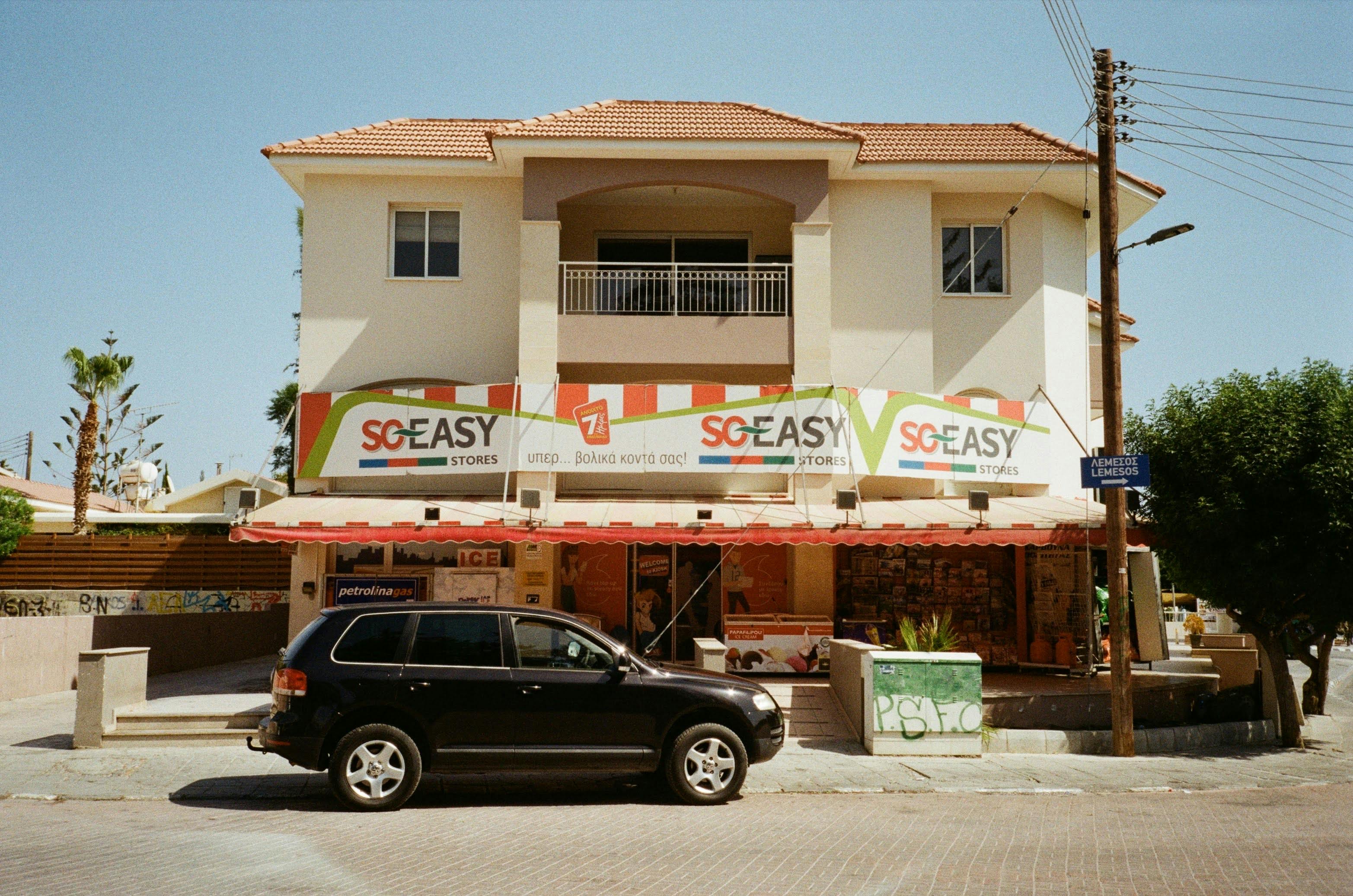 Street view of a convenience store in Cyprus with a black SUV parked outside. - Photo by Liza Bakay on Pexels