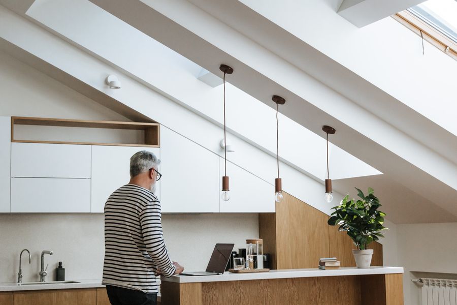 A senior man with grey hair working at a laptop in a stylish, modern home office.