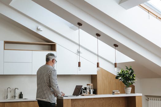A senior man with grey hair working at a laptop in a stylish, modern home office.