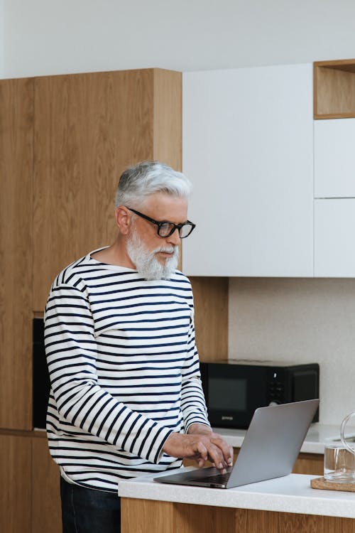 

A Bearded Man in a Striped Shirt Using a Laptop