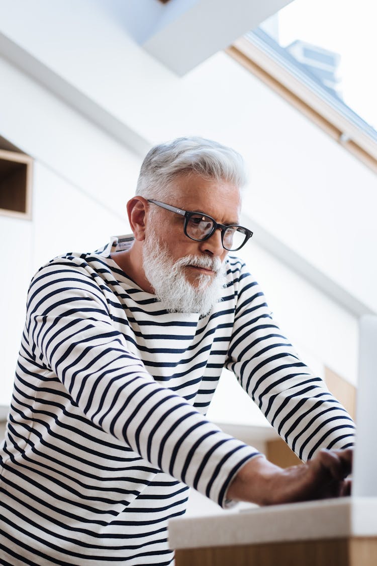 A Low Angle View Of A Senior Male Adult Using A Laptop at Home