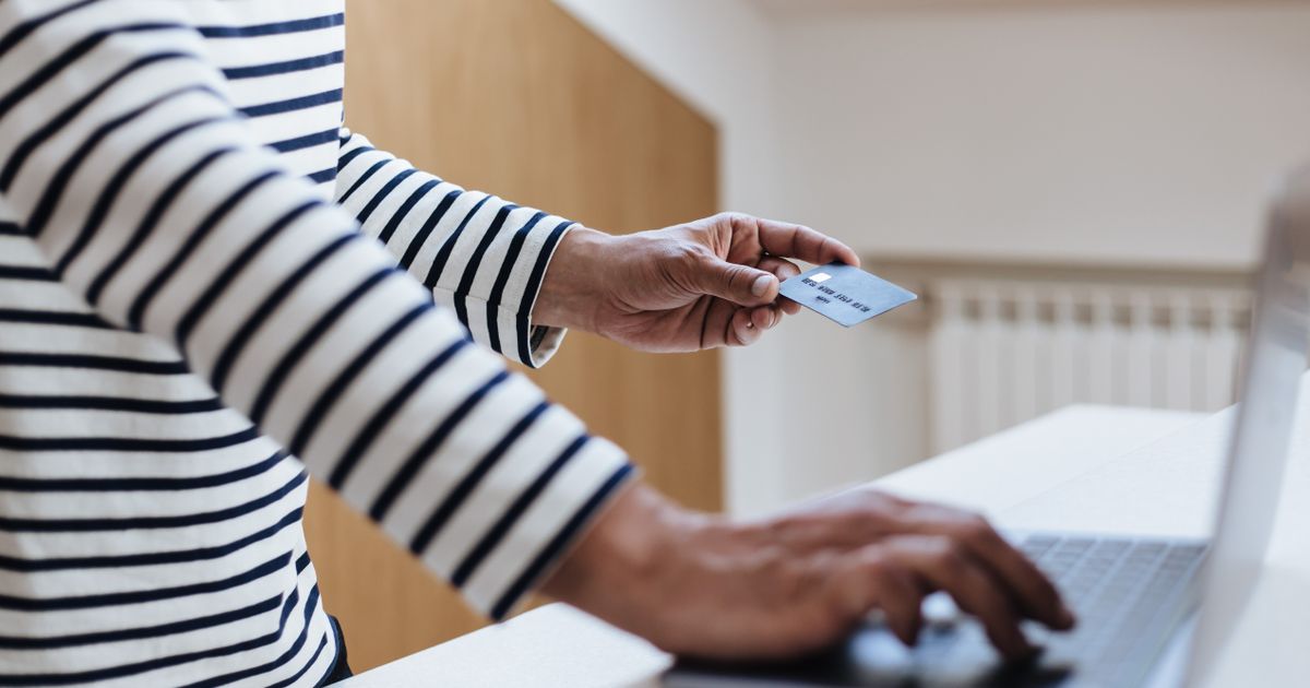 Pessoa comprando online no notebook com cartão na mão