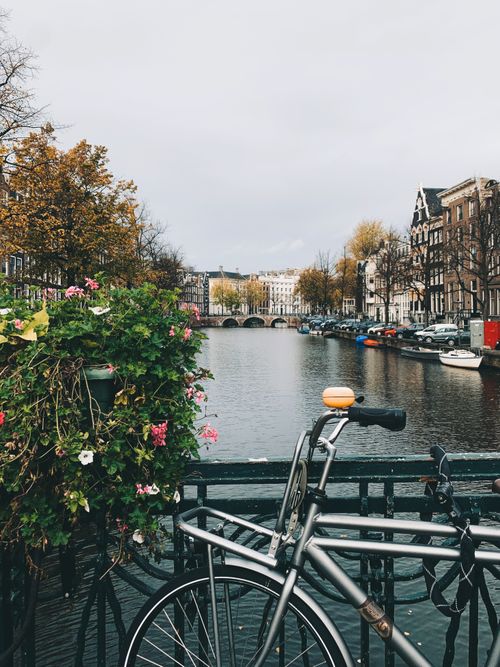 Free Scenic view of Amsterdam canal with parked bicycles and autumn foliage. Stock Photo
