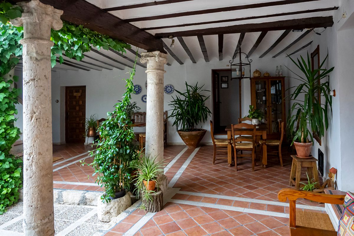 Patio spaniol rustic cu coloane de piatra, grinzi de lemn si pardoseala de teracota