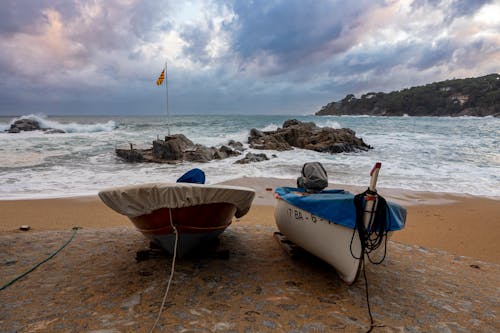Free Photo of Two Boats on Seashore and Flagpole on a Rock Stock Photo