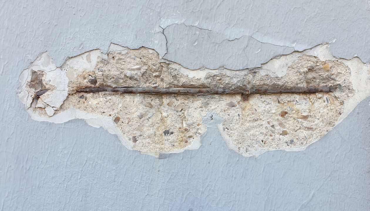 Armature d'acier rouillée mise à nu par l'éclatement du béton d'un mur