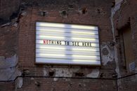 An old marquee on a weathered brick wall displaying the phrase 'Nothing to See Here.'