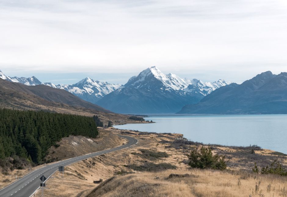 Scenic New Zealand road trip through mountains with a visible cell tower in the distance