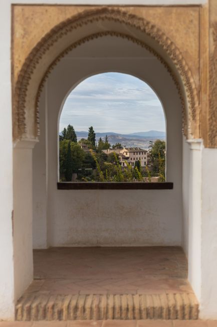 View of Granada through a historical archway, showcasing the city's classic architecture.