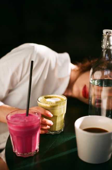 Artistic shot of a woman with vibrant drinks and black straw on a table.