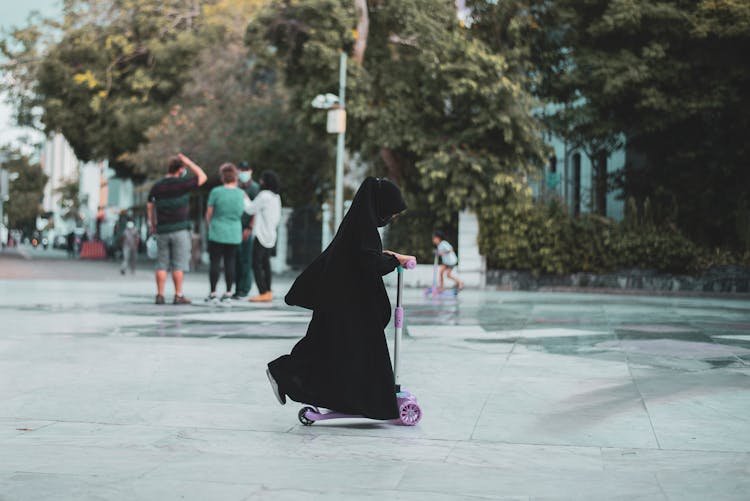 Girl In Black Hijab Playing With A Scooter