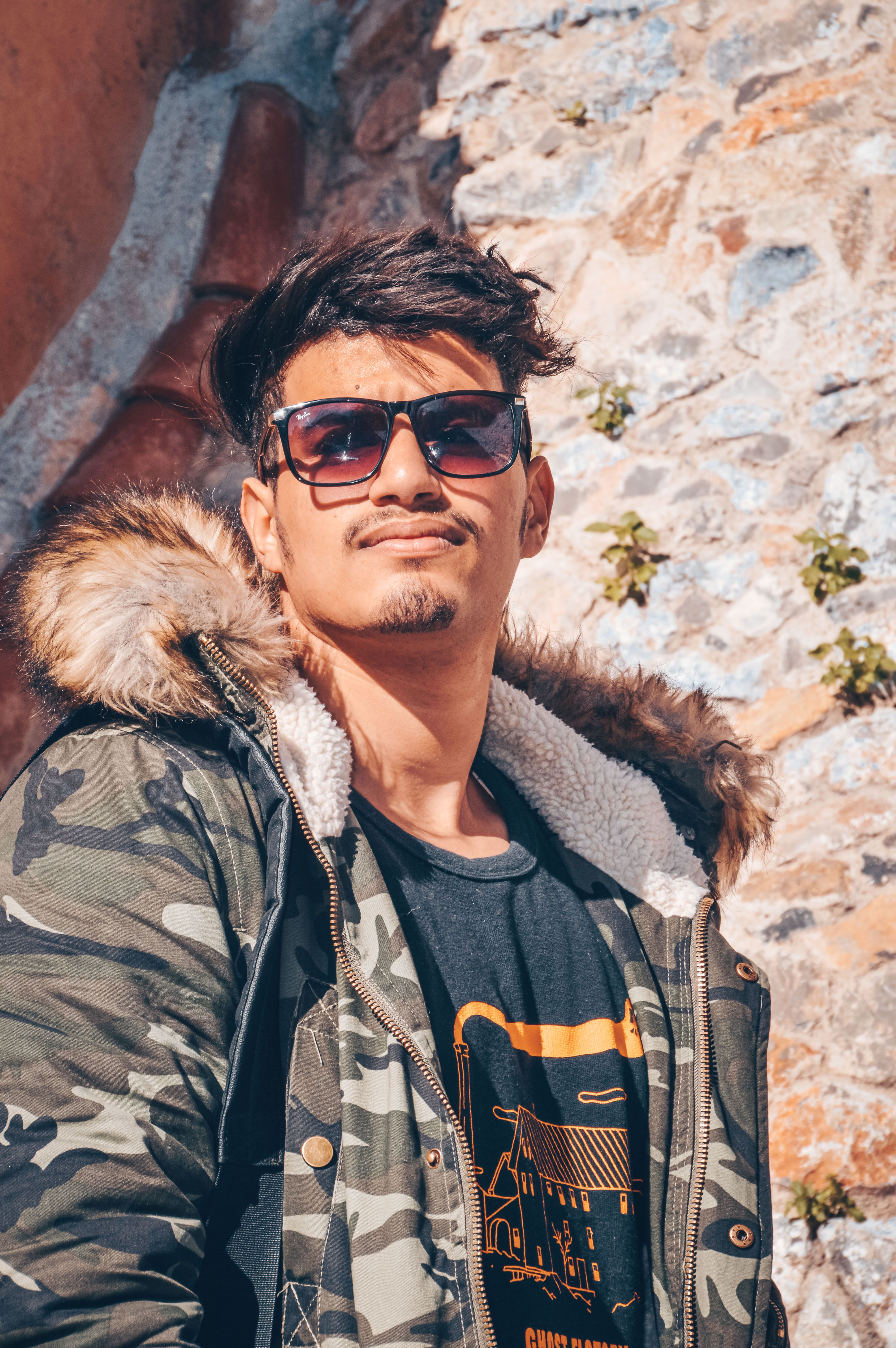 Fashionable young adult wearing sunglasses and jacket in sunny Chefchaouen, Morocco.
