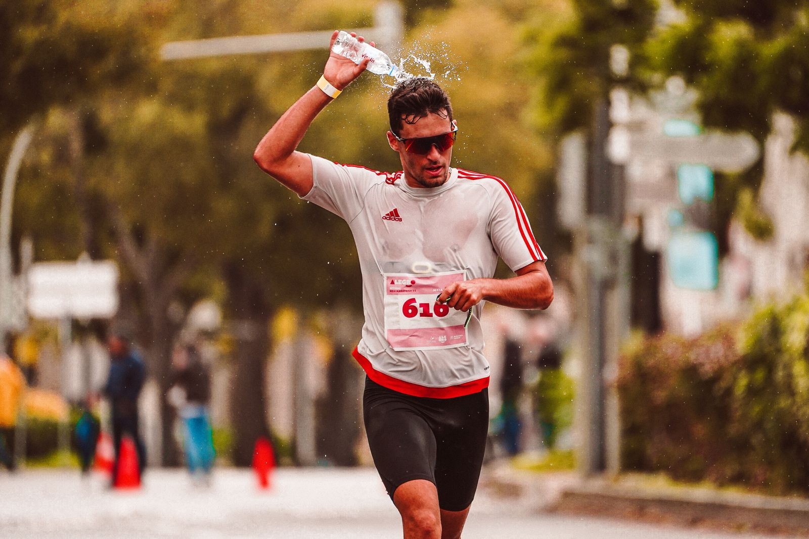 Marathon athlete pouring water over their head to cool down mid-race — the kind of high-sweat moment when electrolyte choice matters most.
