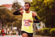 Athlete drinking water while running in a marathon. Outdoor exercise.
