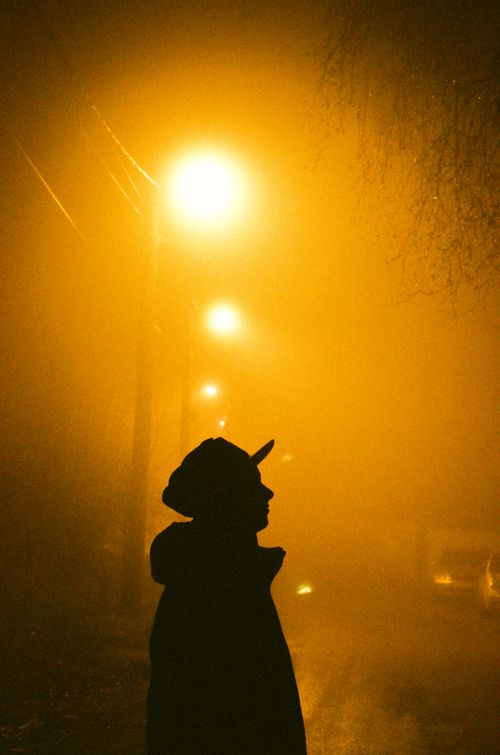 Free Misty street scene with silhouette of a person under street lamps glowing in fog. Stock Photo