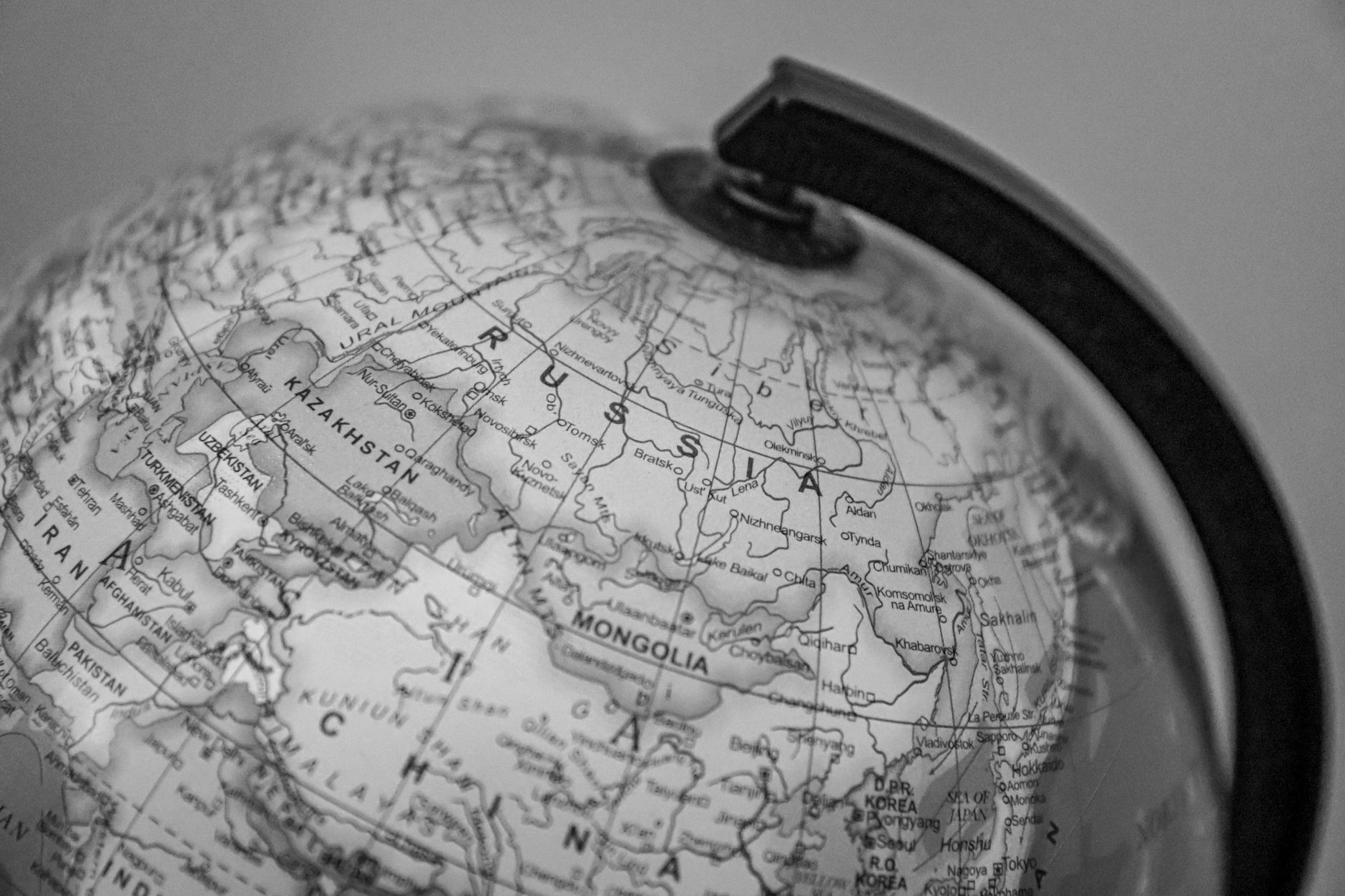 Black and white close-up of a globe focusing on Russia and surrounding countries.