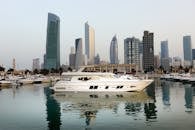 科威特城现代天际线的景色令人惊叹，游艇倒映在码头的水面上